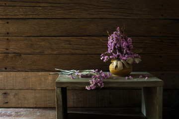 Vase with withered flowers on the old wooden chair and wooden table / still light image