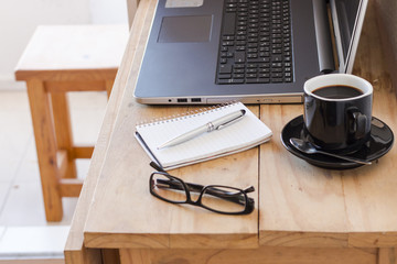 Workplace with a laptop, coffee, notebook and a glasses