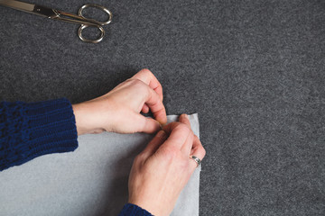 Hands of seamstress fixing template to fabric