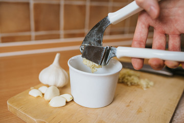 Garlic crushed squeezed from garlic press with white bowl. © hurvajs