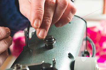 Seamstress hands placing thread in sewing machine