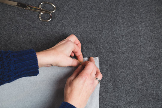 Hands of seamstress fixing template to fabric
