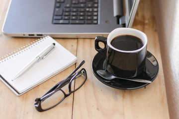 Workplace with a laptop, coffee, notebook and a glasses