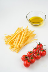 Uncooked italian pasta, olive oil and tomatoes cherry on a white