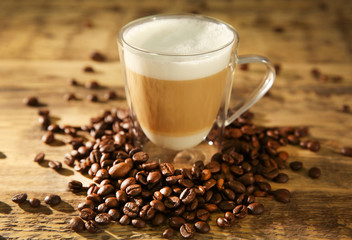 Cup of fresh coffee and beans on wooden background