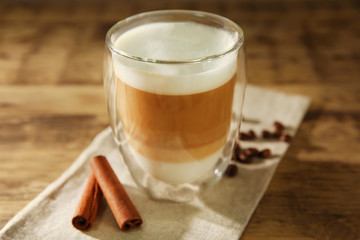 Cup of fresh coffee with cinnamon on wooden background