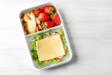 Lunch box with food on wooden background, top view