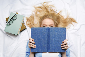 Beautiful girl reading book on bed
