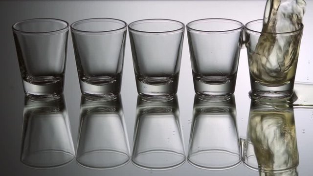 Tequila shots being poured, slow motion.