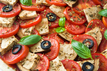 Vegetarian pizza with eggplant, tomato, black olives, oregano and basil on wooden background