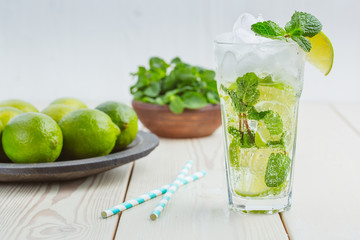 Fresh mojitos cocktail on wooden background. Mojitos with mint leaves, lime and ice. Drink making tools and ingredients for cocktail.
