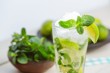 Fresh mojitos cocktail on wooden background. Mojitos with mint leaves, lime and ice. Drink making tools and ingredients for cocktail.