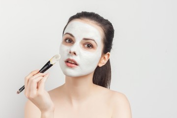 make-up brush and woman in a white mask