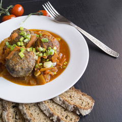 Meatballs in tomato sauce with green onions on a dark background