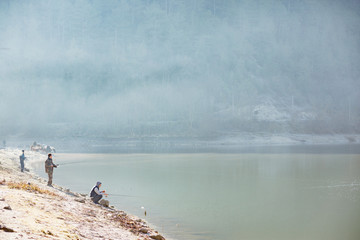 Fischer am See vor dem Wald fangen Fisch