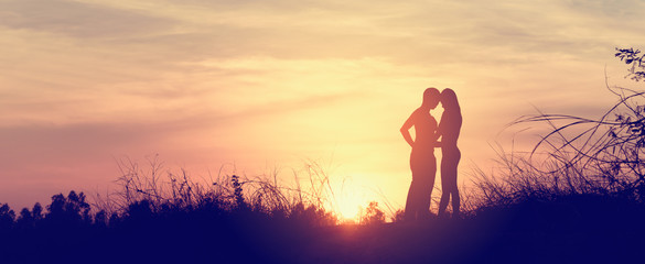 Silhouette of couple kissing at the sunset, panoramic banner bac