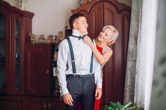 Mother is helping with a bow-tie to her son before wedding ceremony. Concept mother and son.