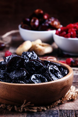 Prunes in wooden bowl, rustic style, selective focus