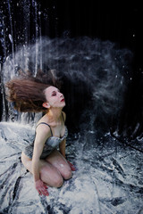 Girl dancer jumping and dancing in the white dust with flour on