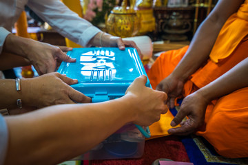 People making a merit by offering things to a Buddha monk