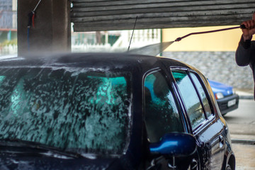 Car Wash Closeup. Washing Car by High Pressure Water