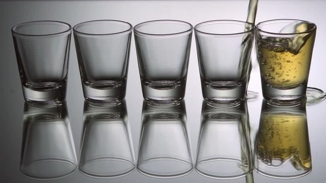 Pouring tequila shots, slow motion.