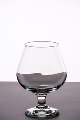 Empty brandy glass on the whte grey beckground