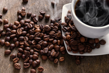 Coffee cup and beans on texture wooden table.