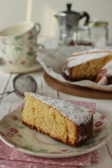 Fetta di dolce su piattino e tavolo imbandito per la colazione