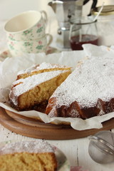 Torta tagliata a fette su tavolo con tazze e moka