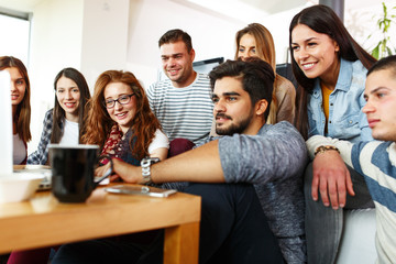 Friends sitting together in living room and watching movie on on laptop.Home party.