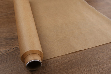 Baking paper on wooden background. Roll of butter paper on table with empty place for your design.