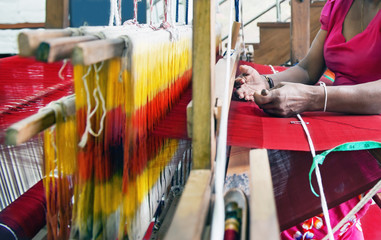 Woman weaves  with wooden weaving loom