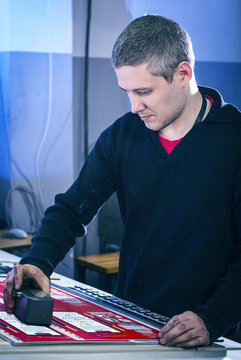 Young man in the process of offset printing and color correction