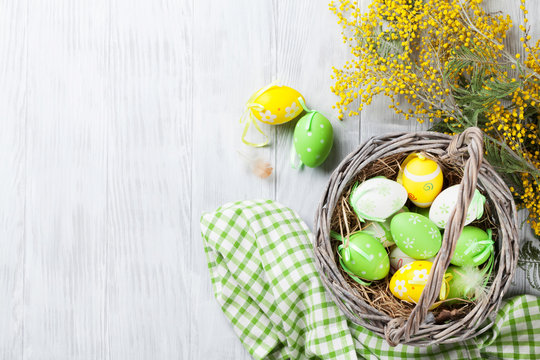 Colorful easter eggs in basket and mimosa