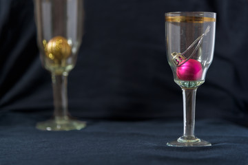 Christmas toy balls in a glasses of champagne. Black background.