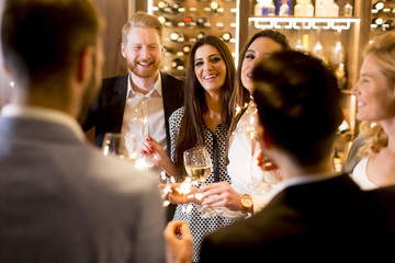 Group of young people celebrating and toasting with white wine