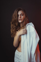 Beautiful young woman posing in men's shirt at studio