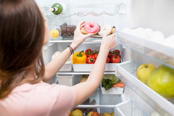 Woman taking sweet donuts from the refrigerator