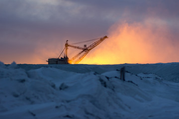 Heavy Mining Excavator in a quarry at sunset