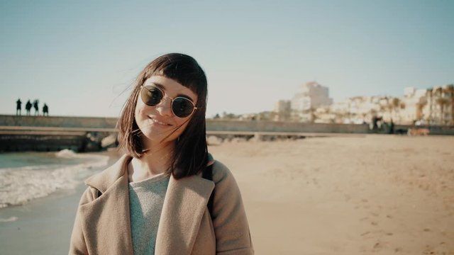 Portrait of peacefully smiling young brunette woman in sunglasses, looking at camera at sunny bright day on sea shore Weekend travelling escape to dicover new locations and adventures