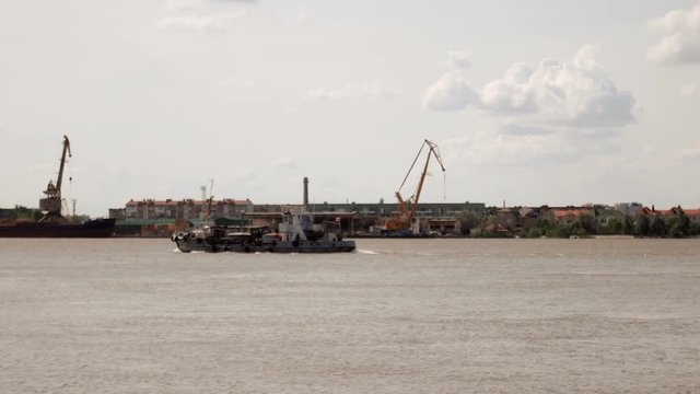Ship sails on the river Volga (View from the Astrakhan Waterfront). Warf cranes on far riverside