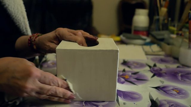 Woman wipes the dust after polishing with the box. Decoupage