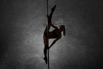 Young pole dancer on gray background