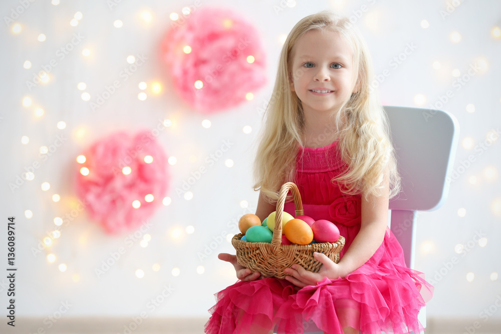 Wall mural cute funny girl with colorful easter eggs sitting on chair at home