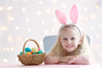 Obraz na płótnie Canvas Cute funny girl with bunny ears and Easter eggs at home