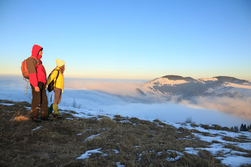 Obraz premium Young couple hiking outdoors with backpacks in winter mountains