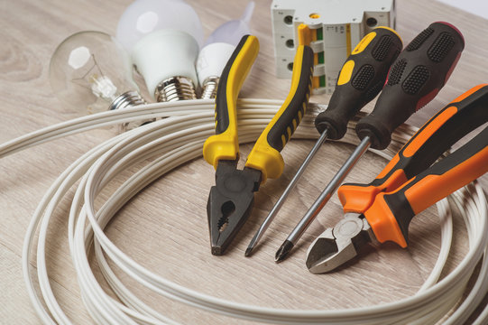 set of electrician tools, a coil of wire and equipment in backgr
