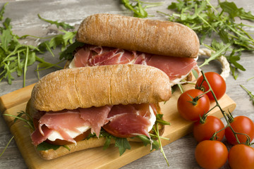 Italian sandwich with meat, cheese, tomatoes and arugula 