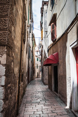 The narrow street in the city with old buildings receding into t